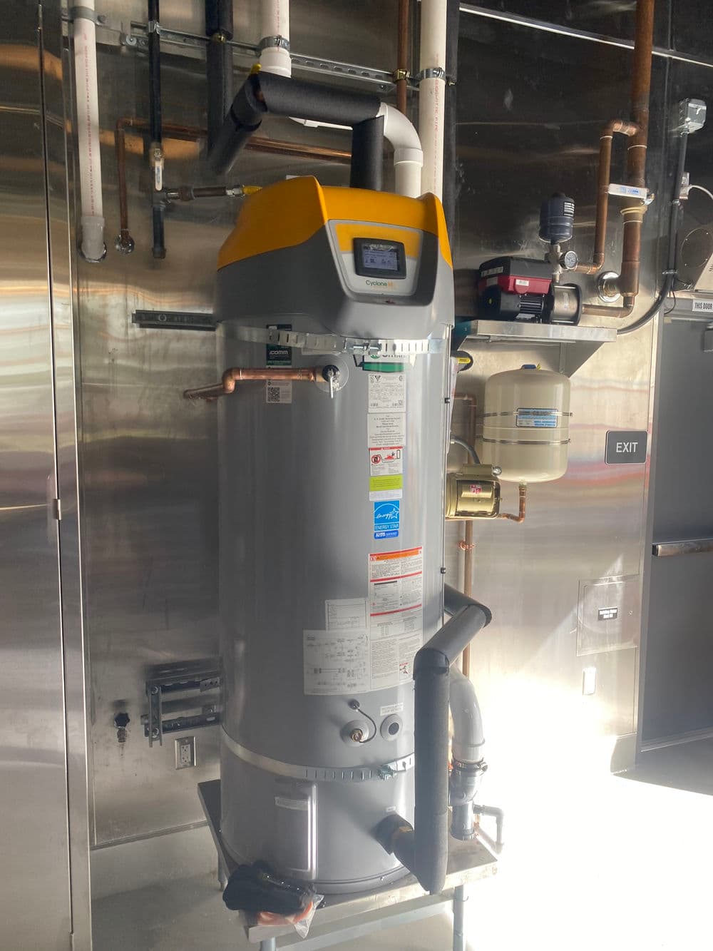 Industrial water heater with digital display and pipes in commercial setting, optimizing energy use.